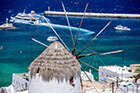 Mykonos. Tradycyjny wiatrak Mylos tou Boni i statki wycieczkowe wychodzące z portu w stolicy wyspy. - foto: wnieznane.pl